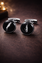 Black cufflinks with silver accents on a dark surface
