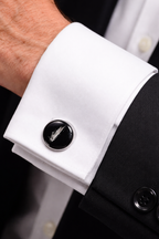 Close-up of a cufflink on a white shirt cuff with a black background