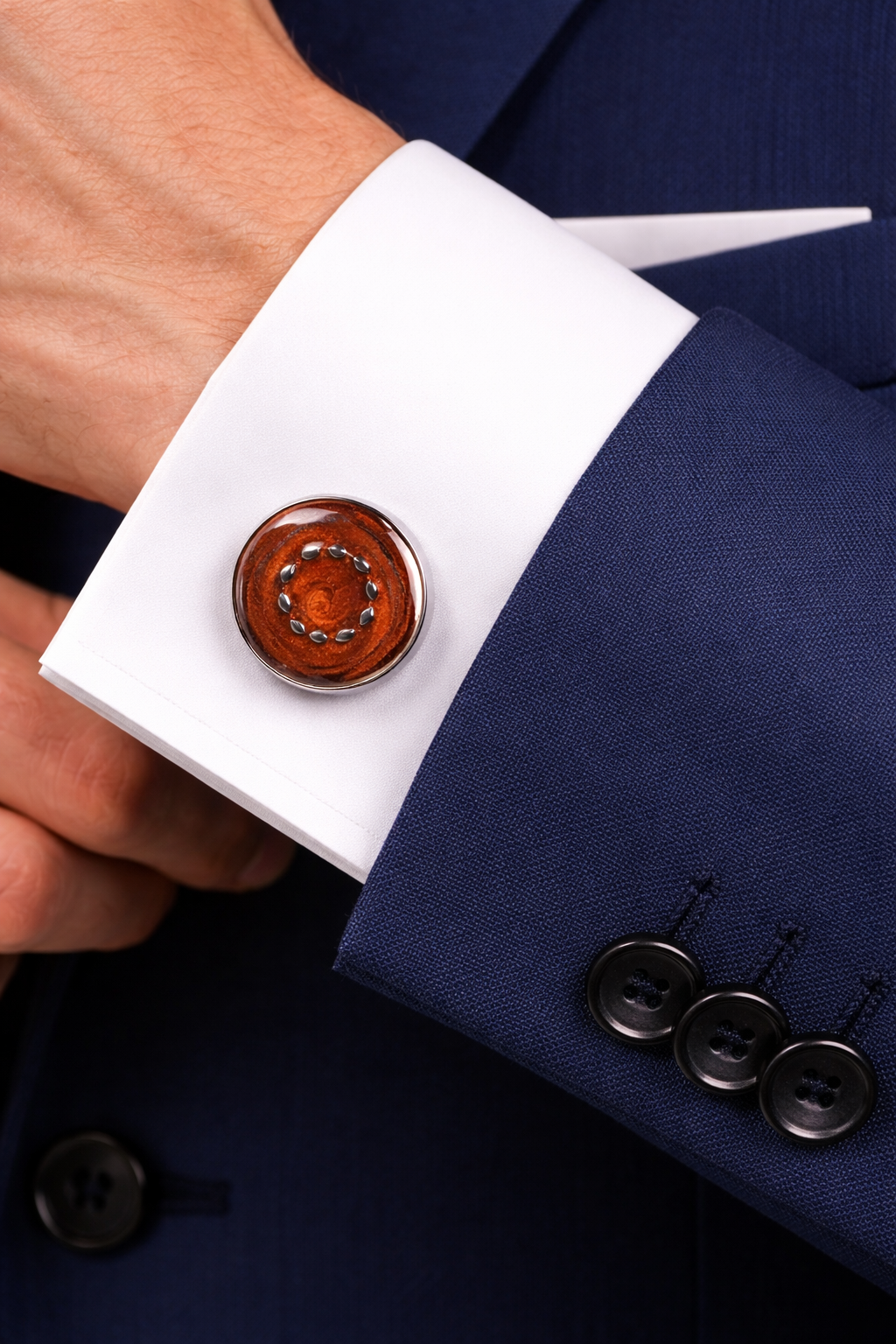 Cufflink on a white cuff against a navy suit background