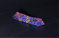 A multicolor necktie with a floral pattern laid out flat on a dark background.