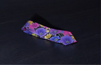 A multicolor necktie with a floral pattern laid out flat on a dark background.