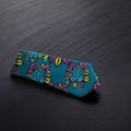 A dark sea green necktie with a floral pattern in pink and yellow, displayed on a dark background.