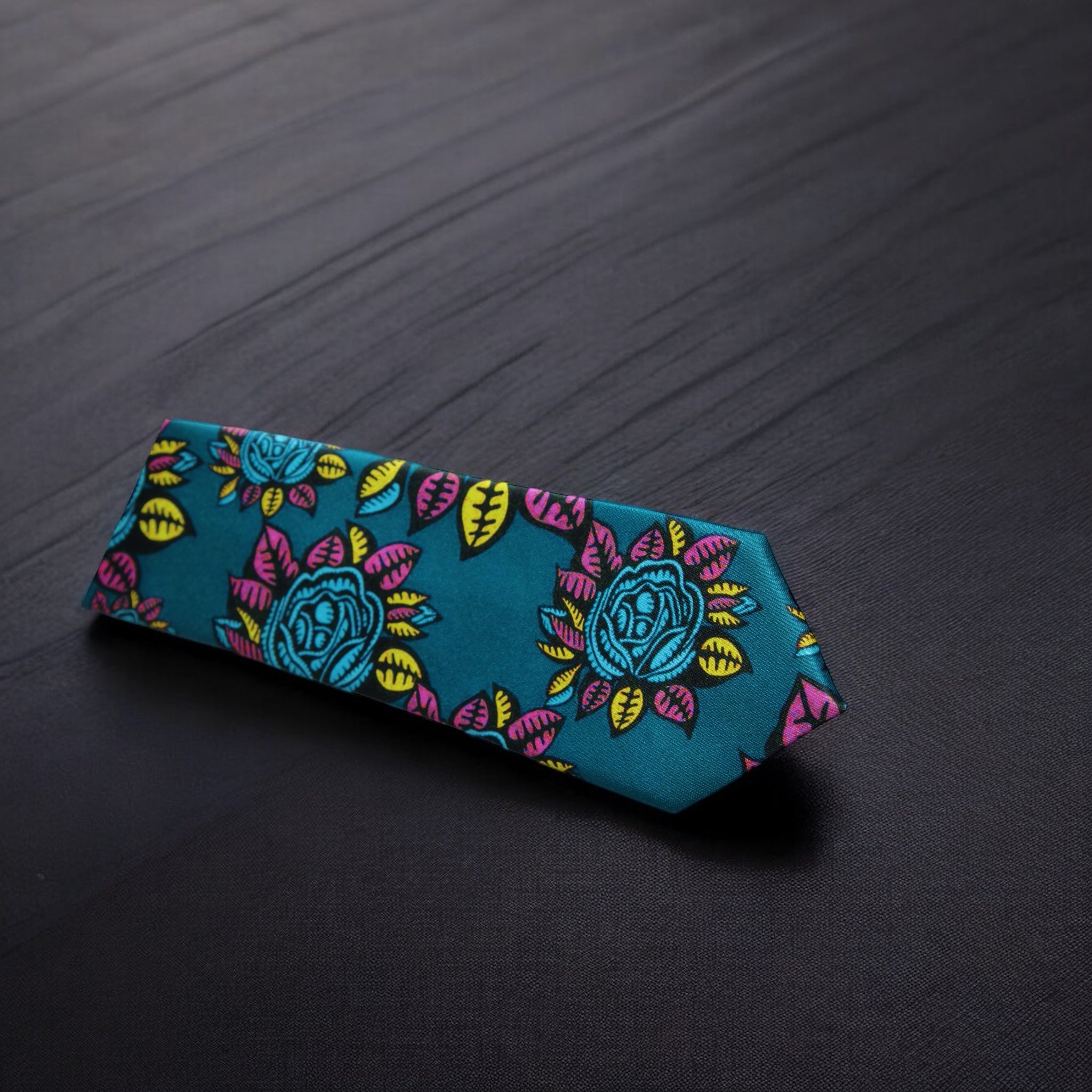 A dark sea green necktie with a floral pattern in pink and yellow, displayed on a dark background.