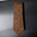 Brown paisley patterned tie on a gray background