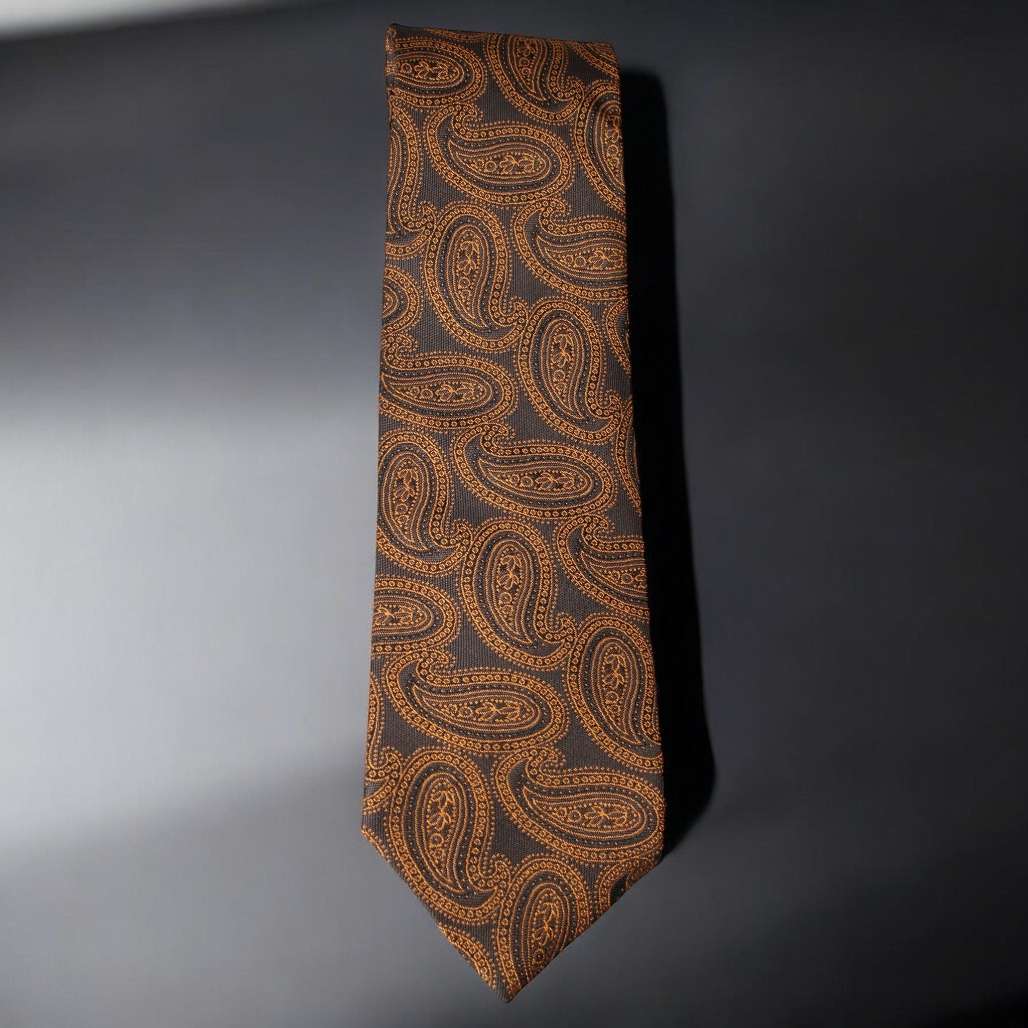 Brown paisley patterned tie on a gray background