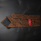 Brown paisley patterned tie with a red tag on a black background