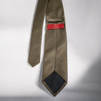 Brown patterned tie with a red label on a light gray background