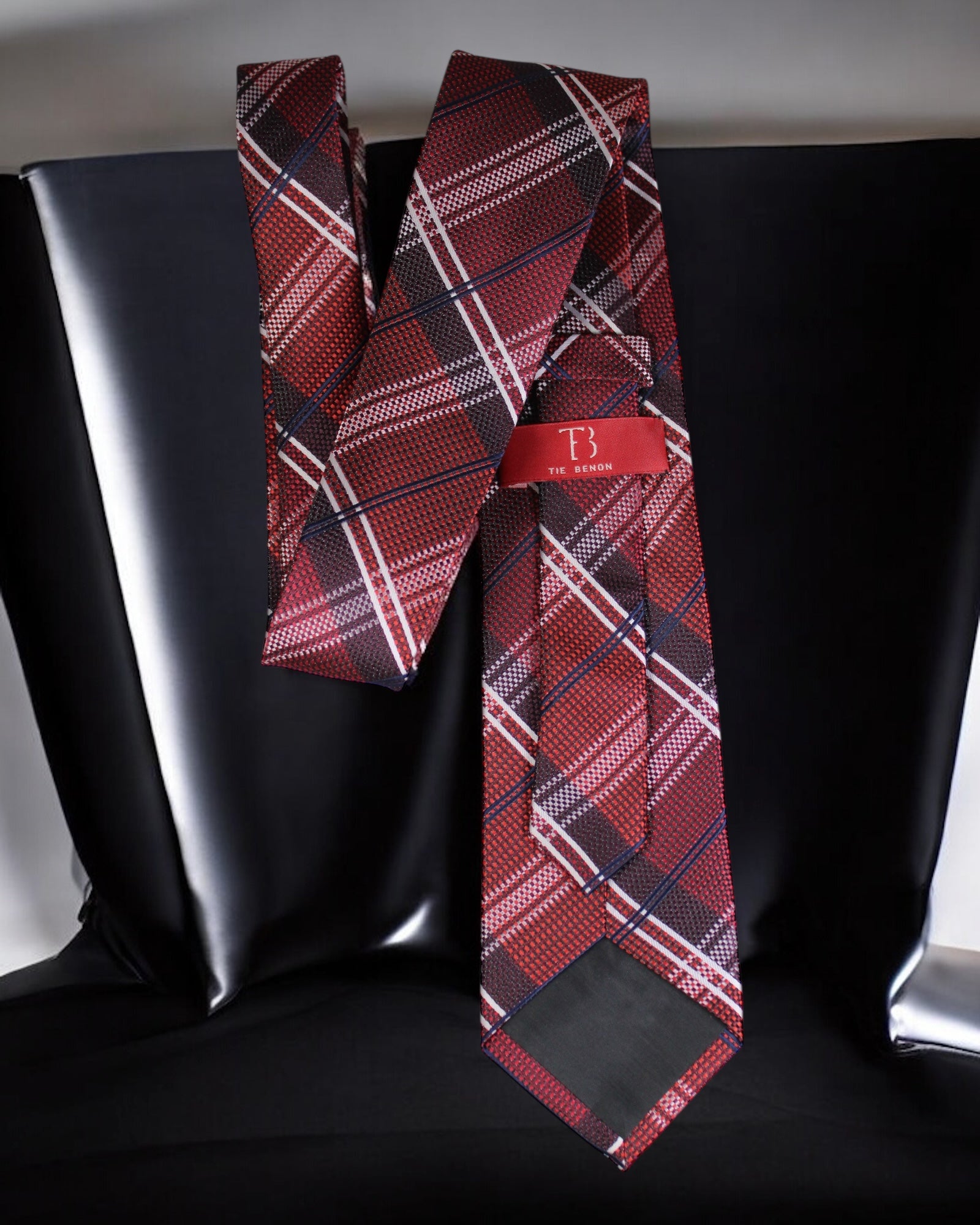 Red plaid tie with a brand label on a black background Tie Benon