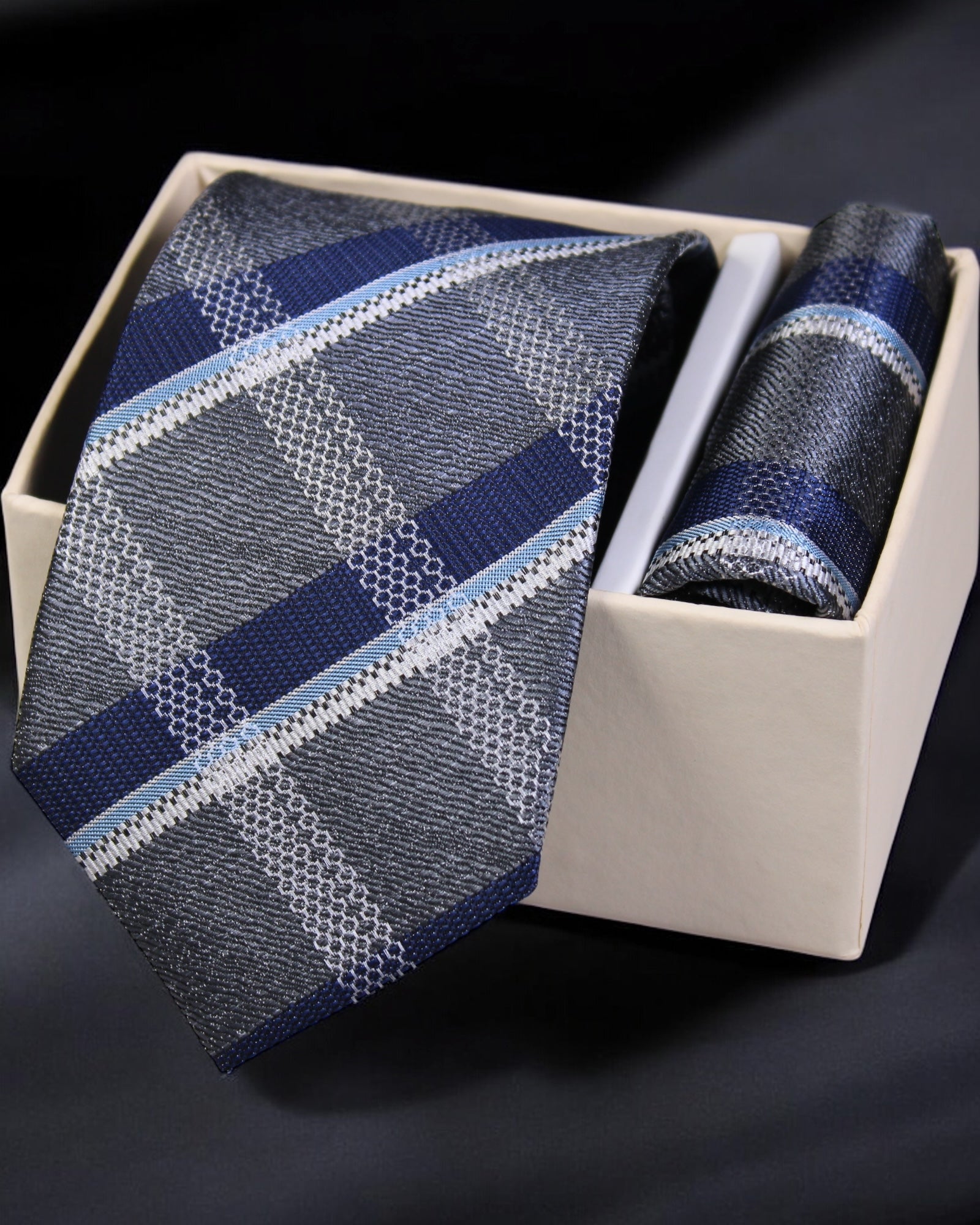 Blue patterned tie and pocket square set in a box on a dark background Tie Benon