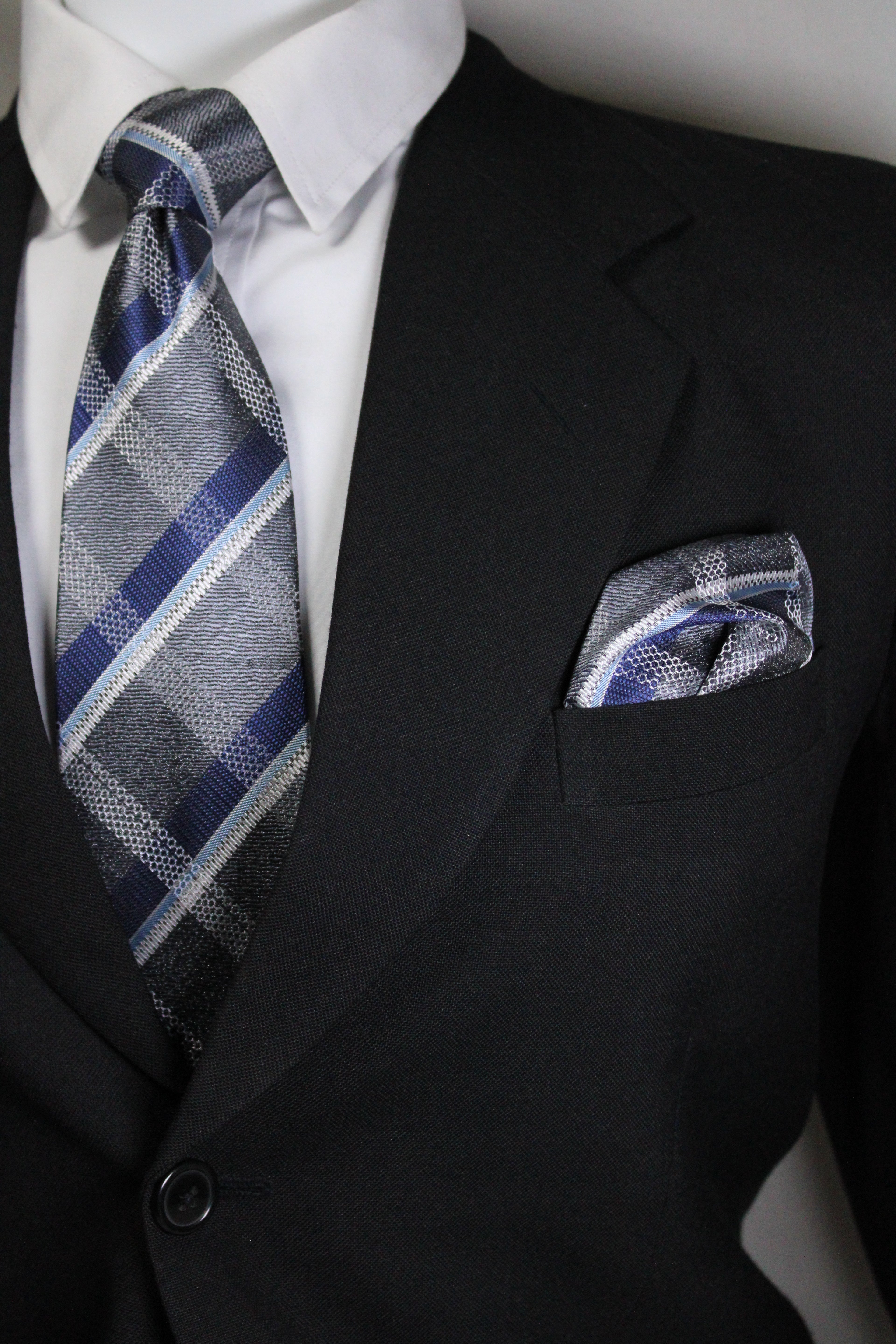 Close-up of a suit with a plaid tie and pocket square Tie Benon