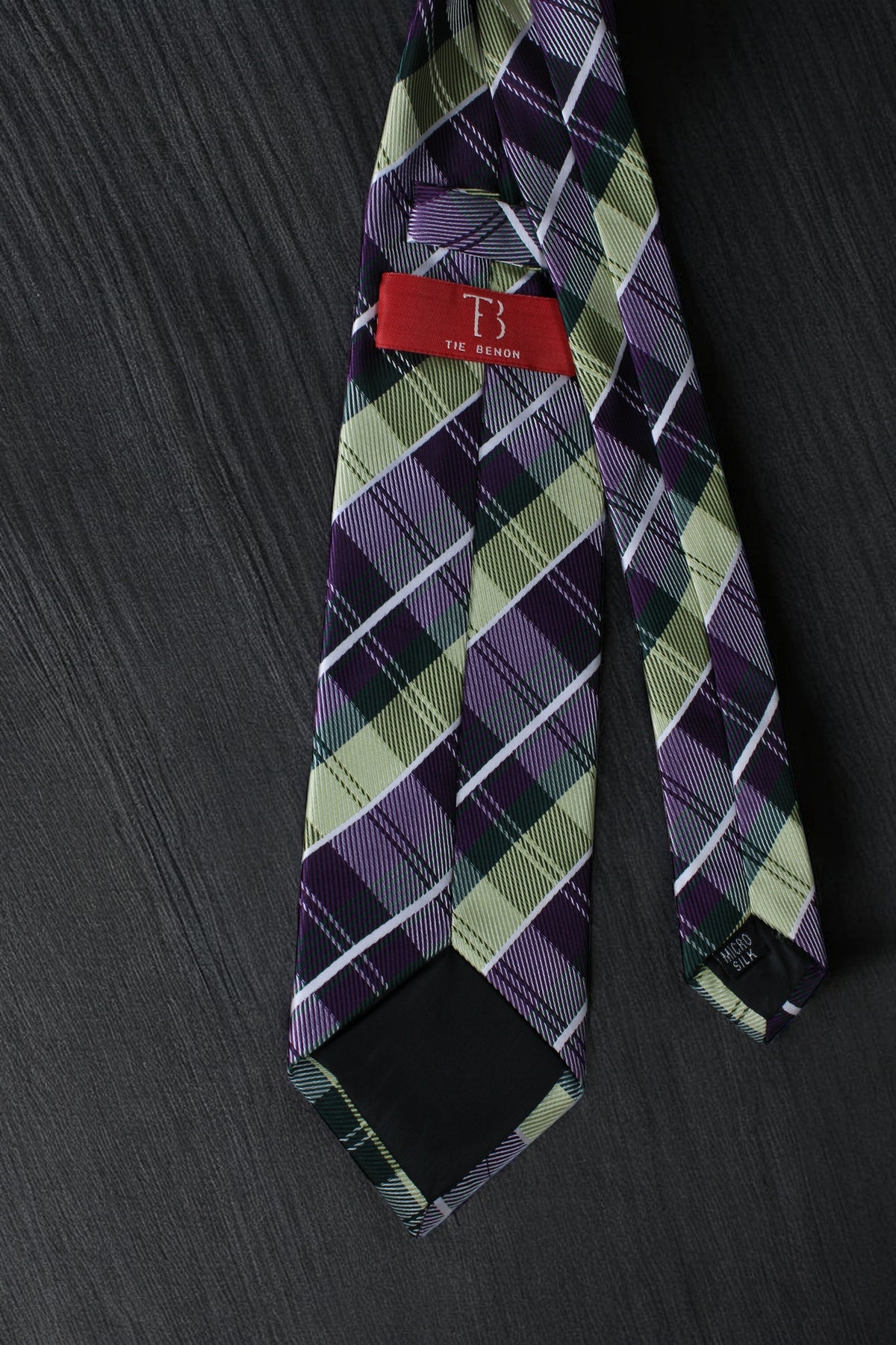 Plaid tie with a brand label on a dark surface