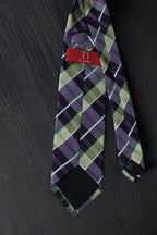 Plaid tie with a brand label on a dark surface