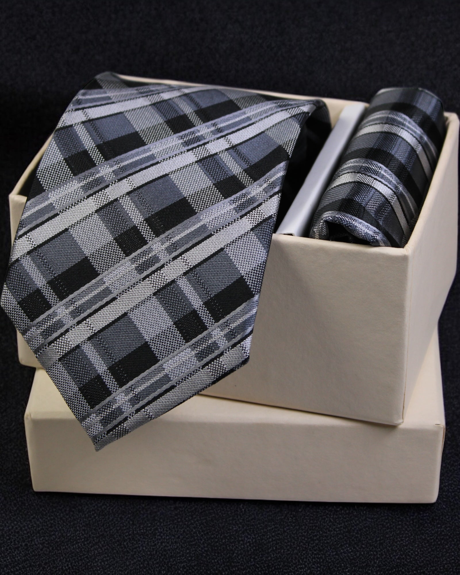 Plaid tie and pocket square set in a box on a black background