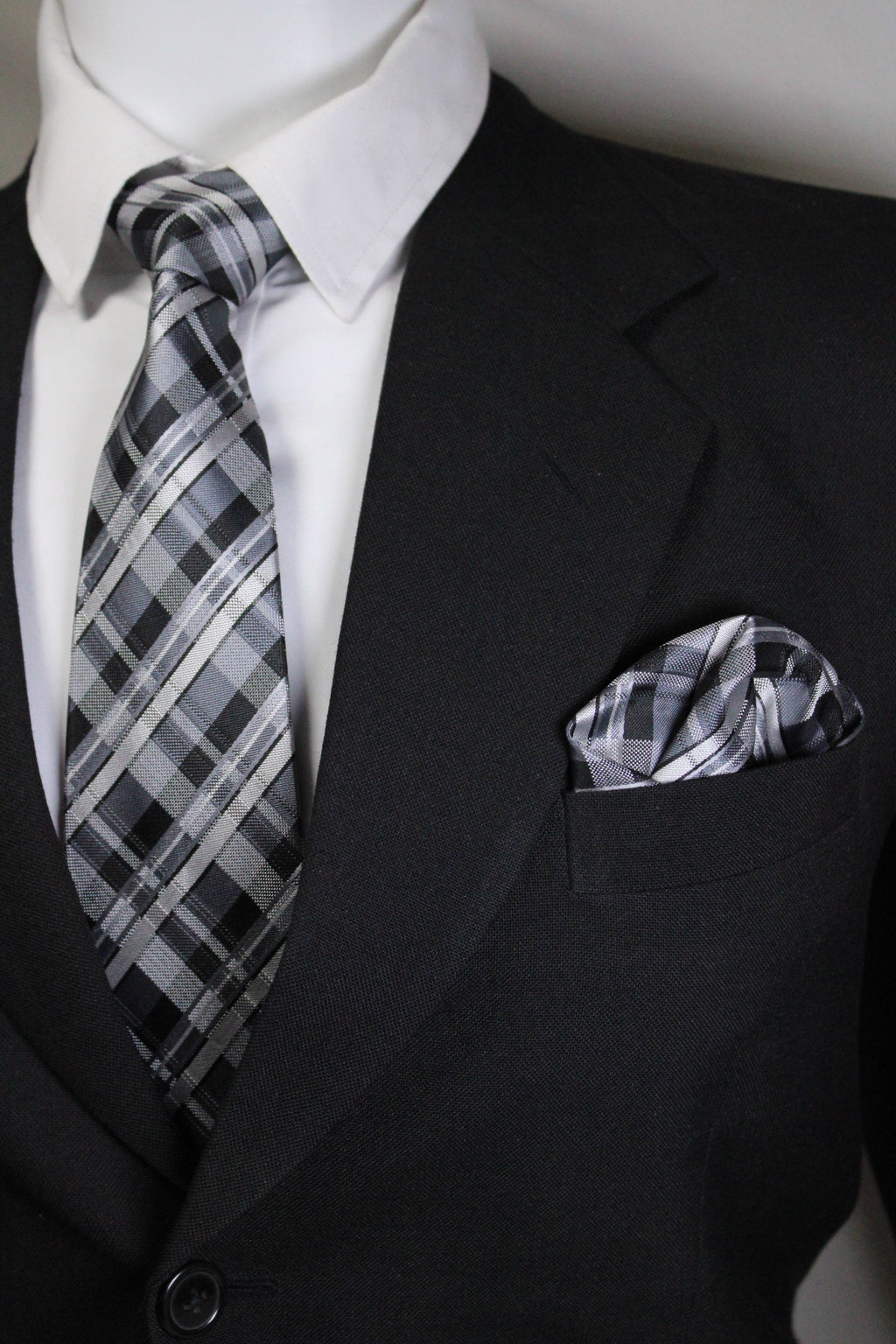 Close-up of a black suit jacket with a plaid pocket square and white shirt.