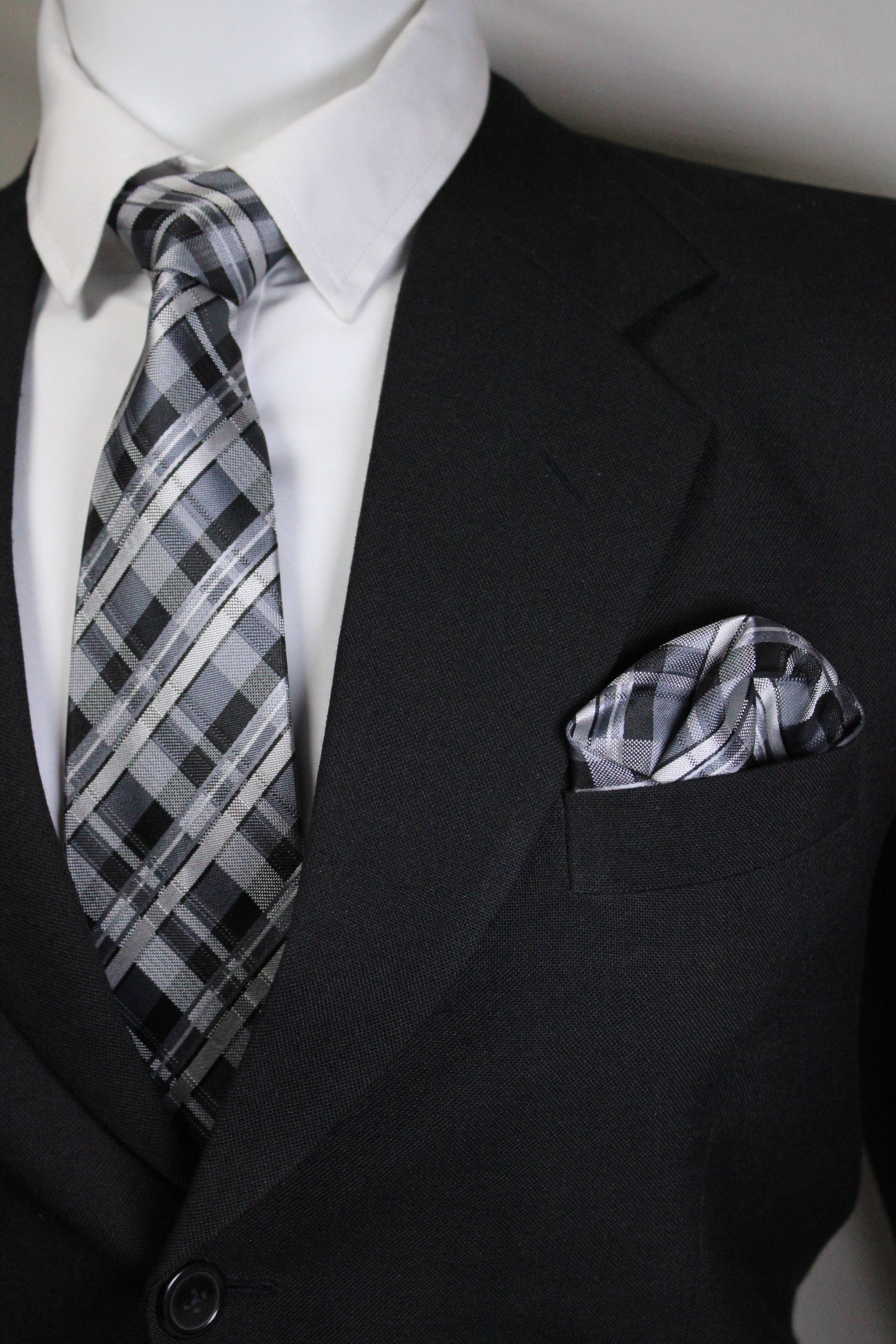 Close-up of a black suit jacket with a plaid pocket square and white shirt.