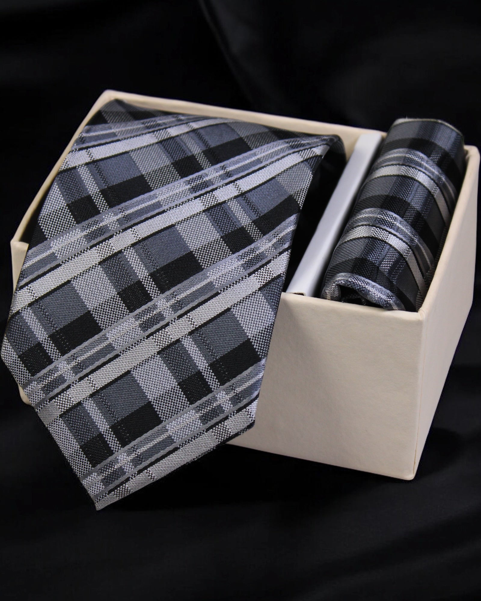 Plaid tie and pocket square set in a box on a black background