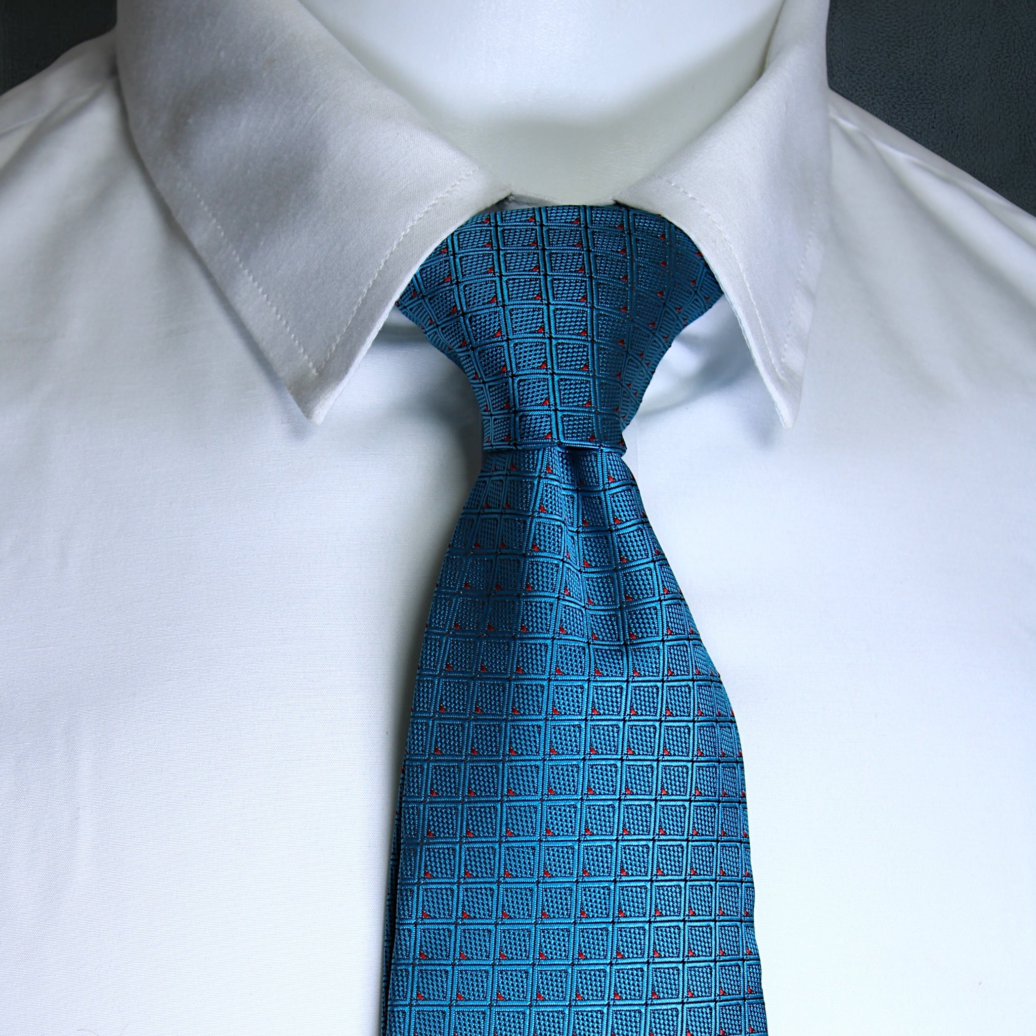 Blue patterned tie on a white shirt against a black background