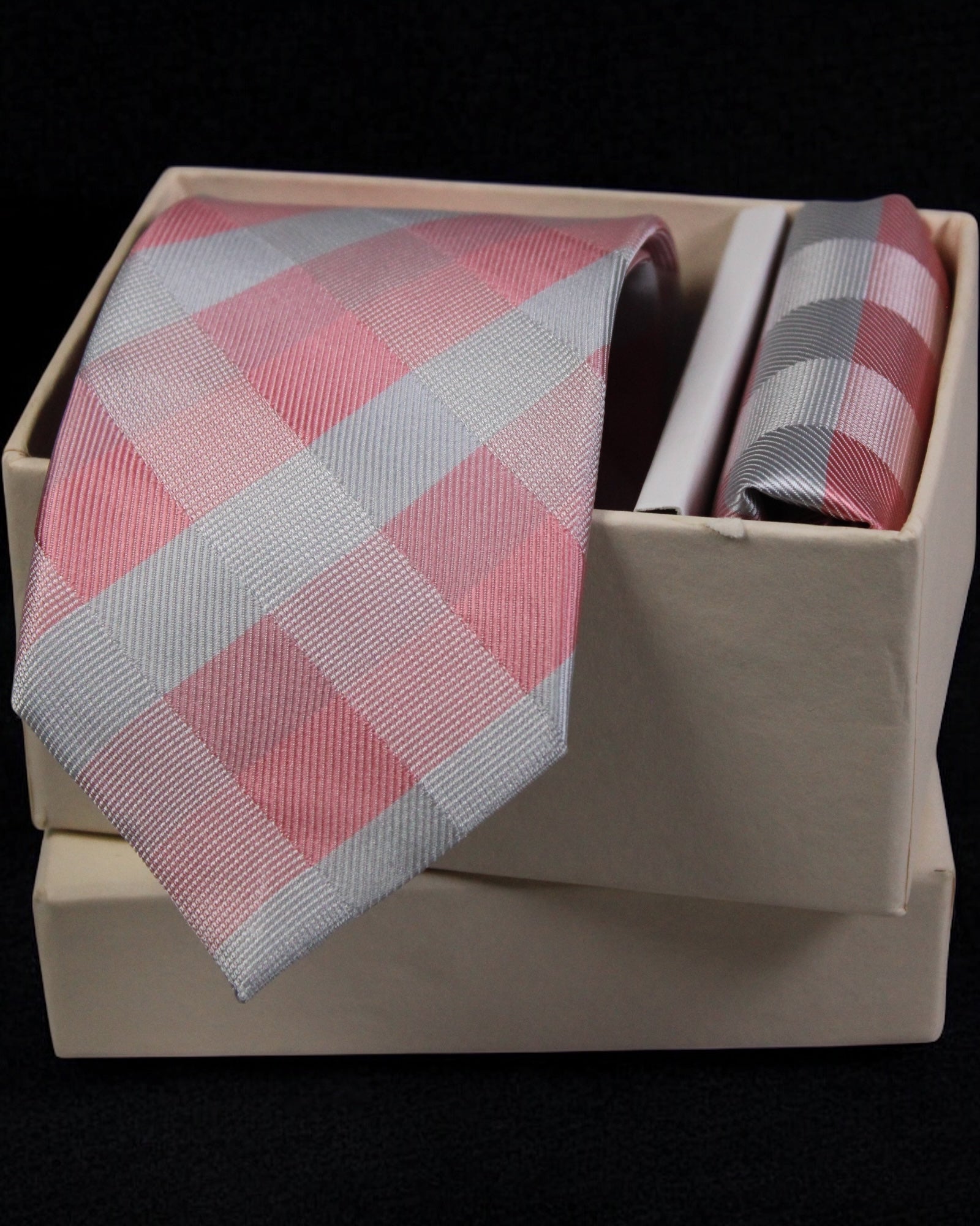 Pink and gray checkered tie and pocket square set in a beige box on a black background