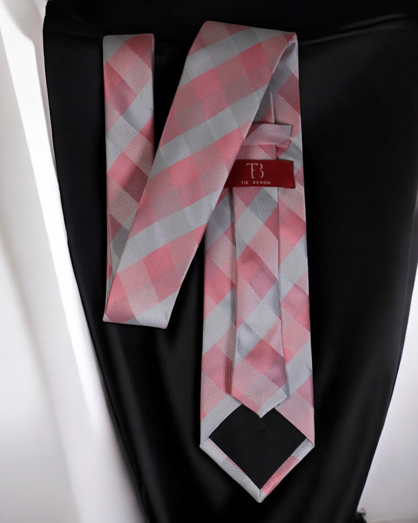 Pink and gray checkered tie with a red label on a black background