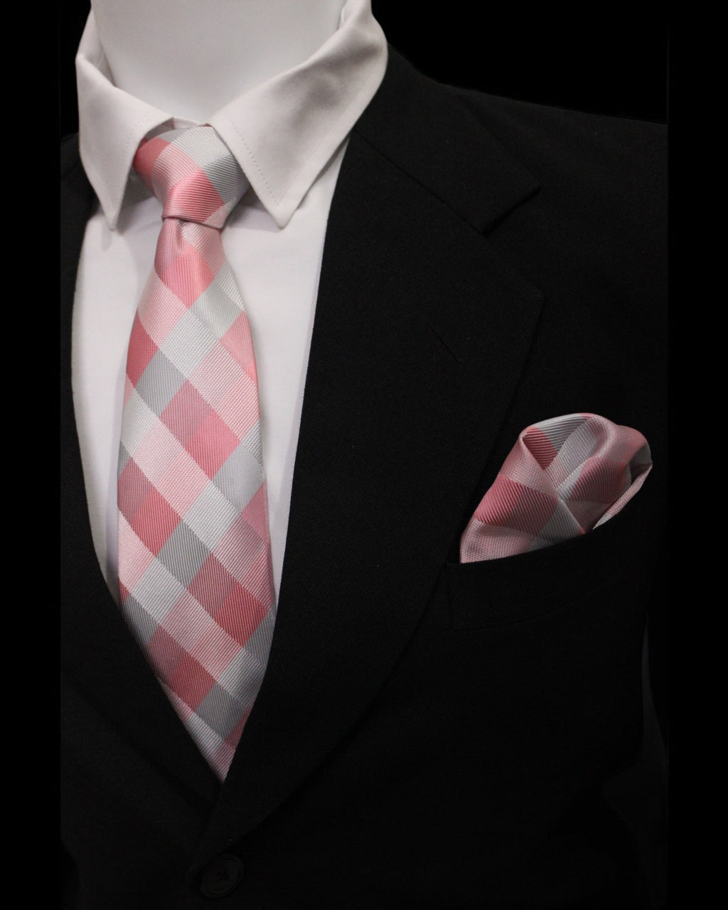 Pink and gray checkered tie and pocket square set against a black suit background