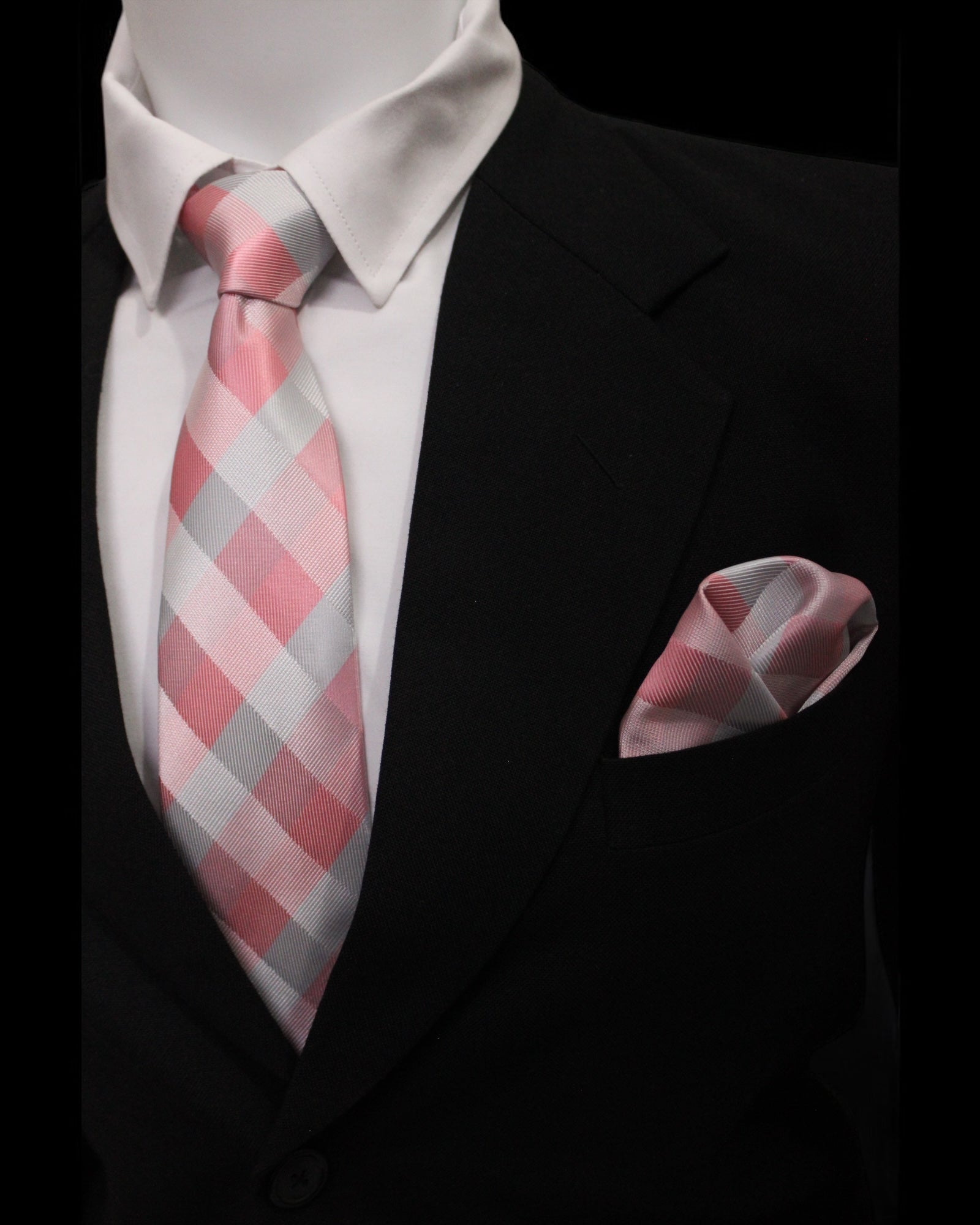 Pink and gray checkered tie and pocket square set against a black suit background