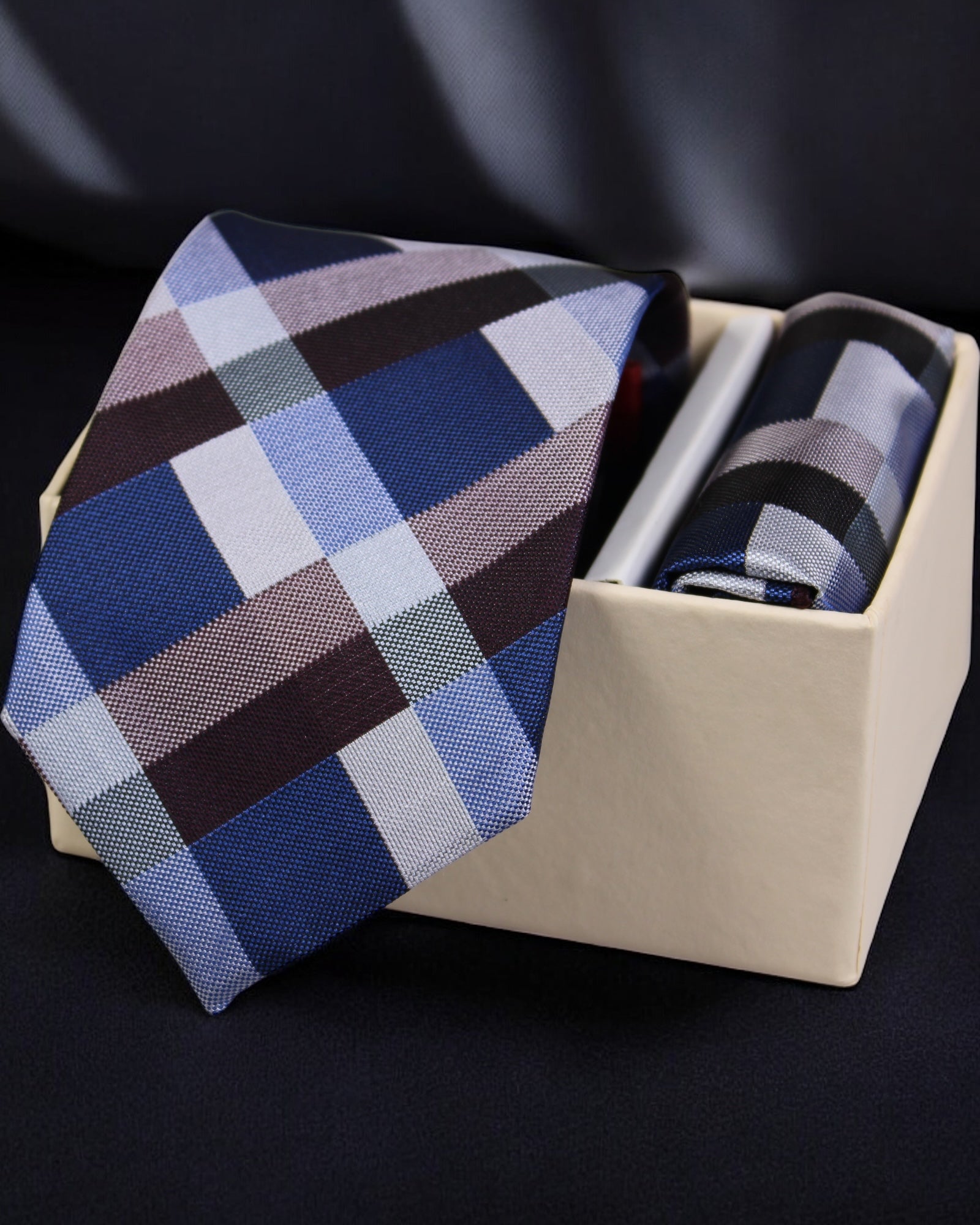Plaid tie in a beige box on a dark background