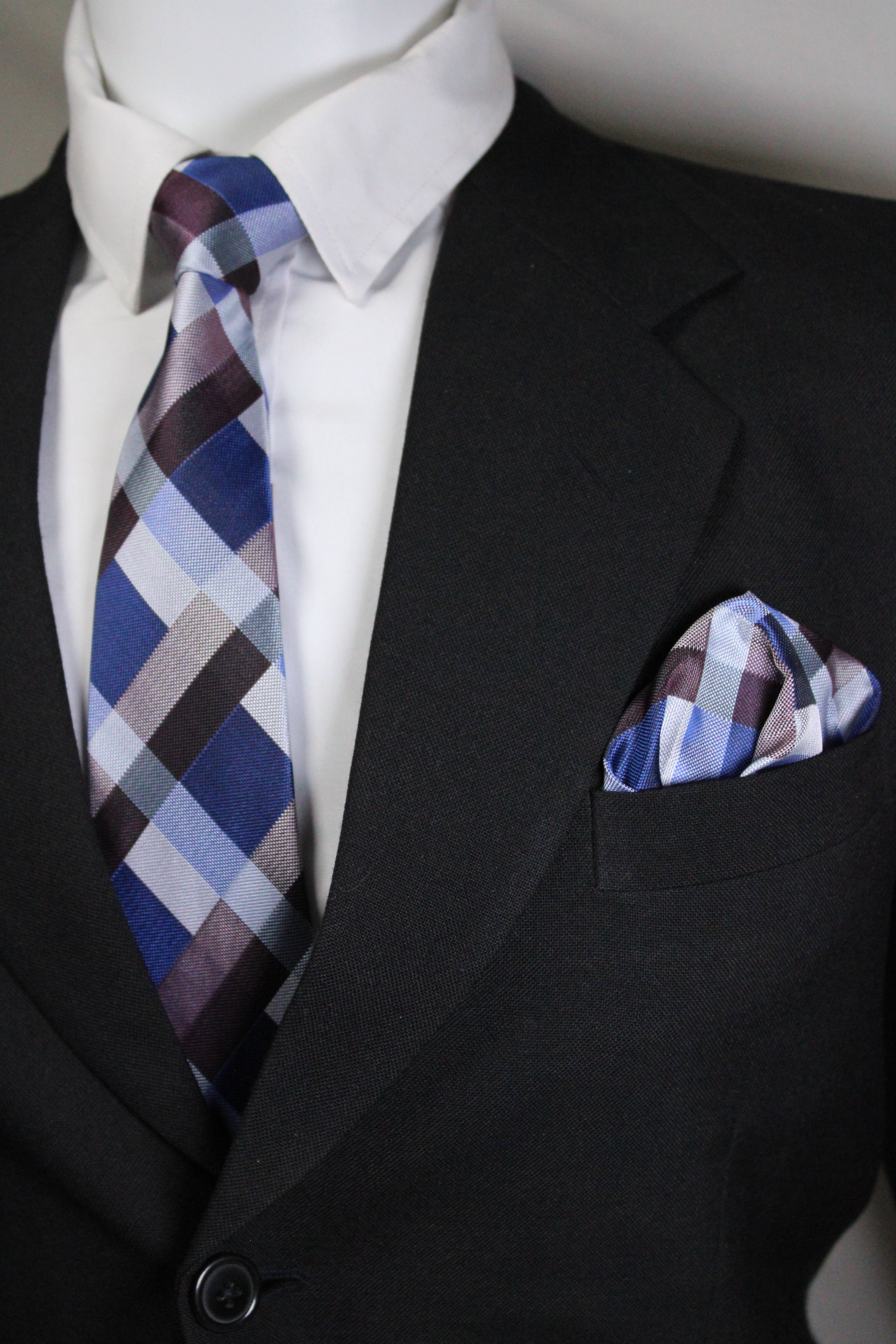 Close-up of a suit with a plaid tie and pocket square.