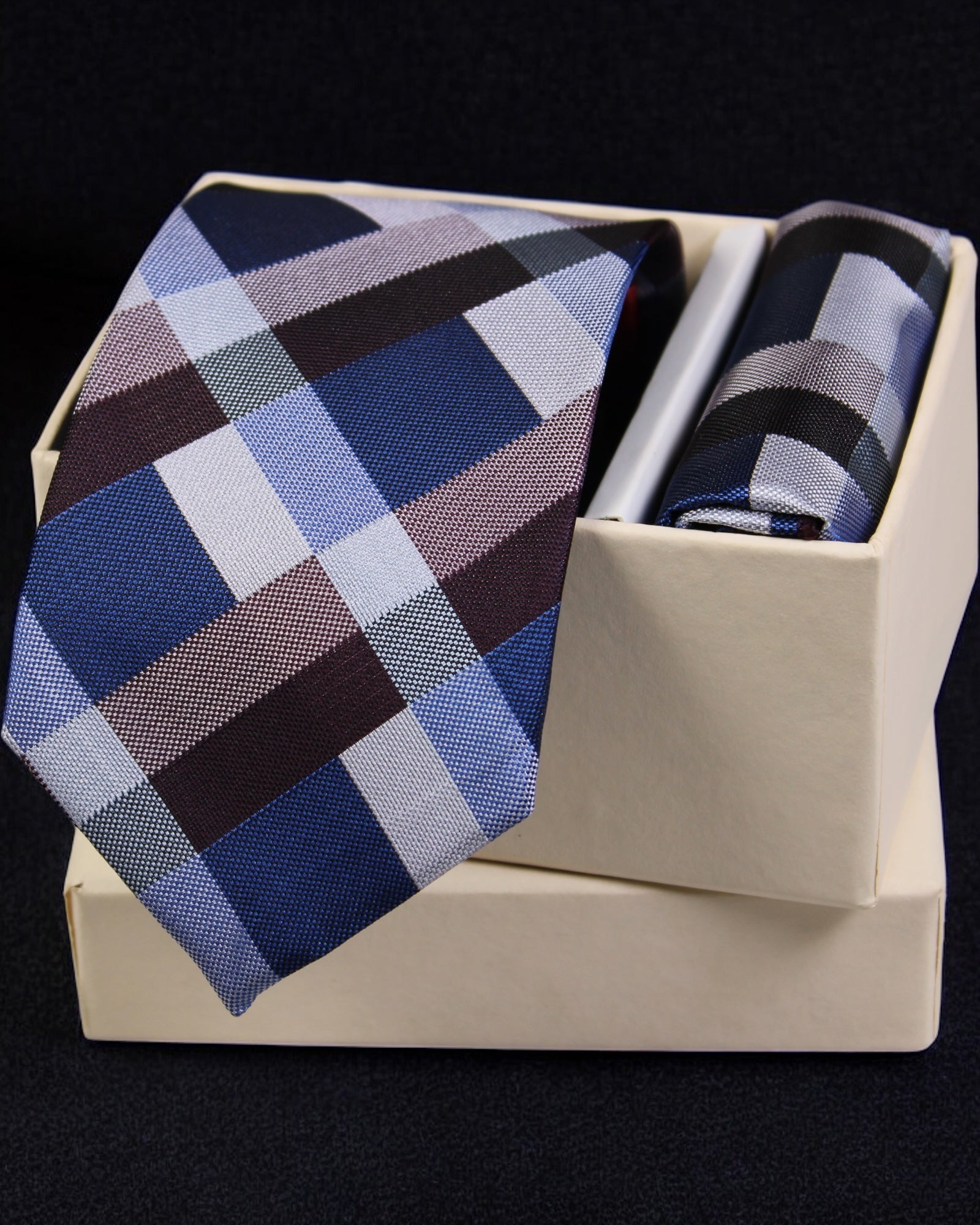 Plaid tie and pocket square set in a box on a black background