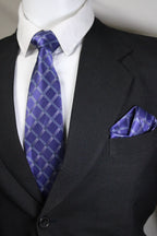 Close-up of a dark suit with a blue patterned tie and pocket square Tie Benon