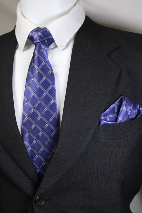 Close-up of a dark suit with a blue patterned tie and pocket square Tie Benon