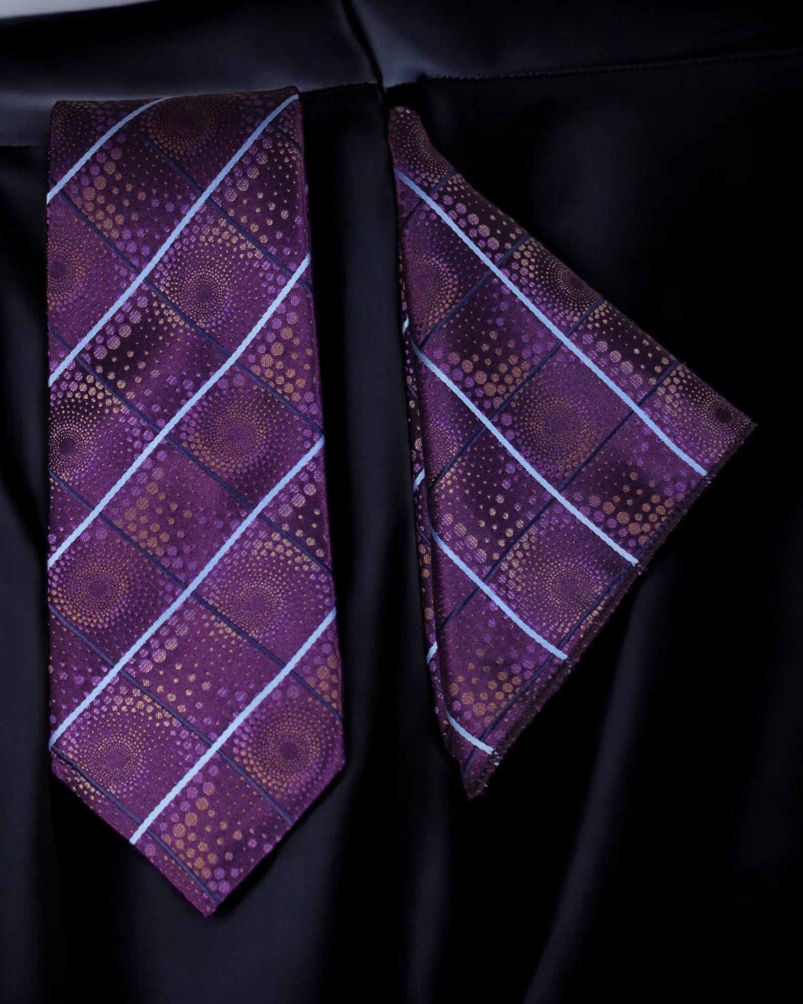 Purple patterned tie and pocket square on a black fabric background Tie Benon
