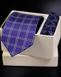 Blue checkered tie and pocket square set in a white box on a dark background tie benon