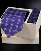 Blue checkered tie and pocket square set in a white box on a dark background tie benon