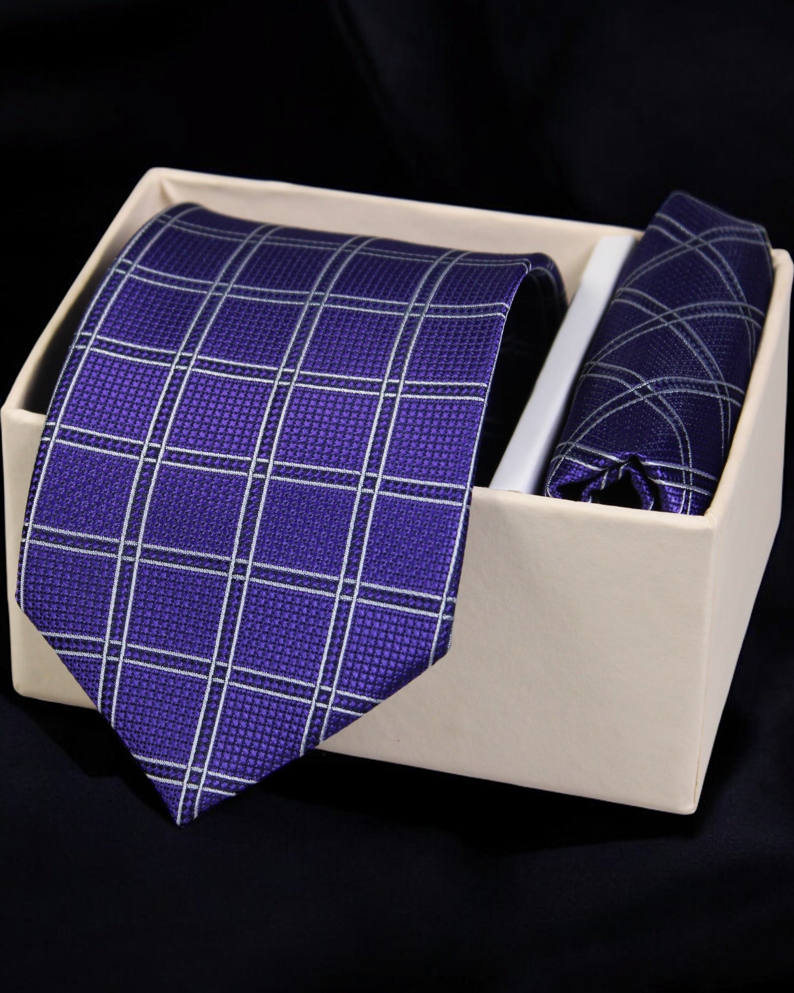 Purple checkered tie and pocket square set in a white box on a black background Tie Benon