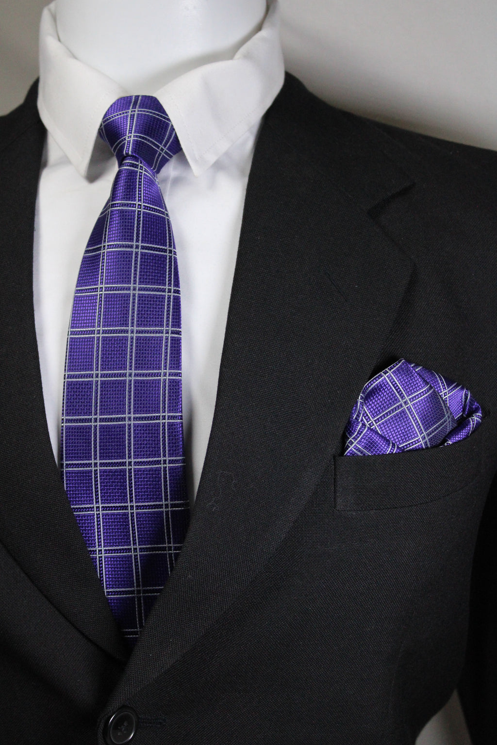 Close-up of a purple plaid tie and pocket square on a black suit jacket Tie Benon