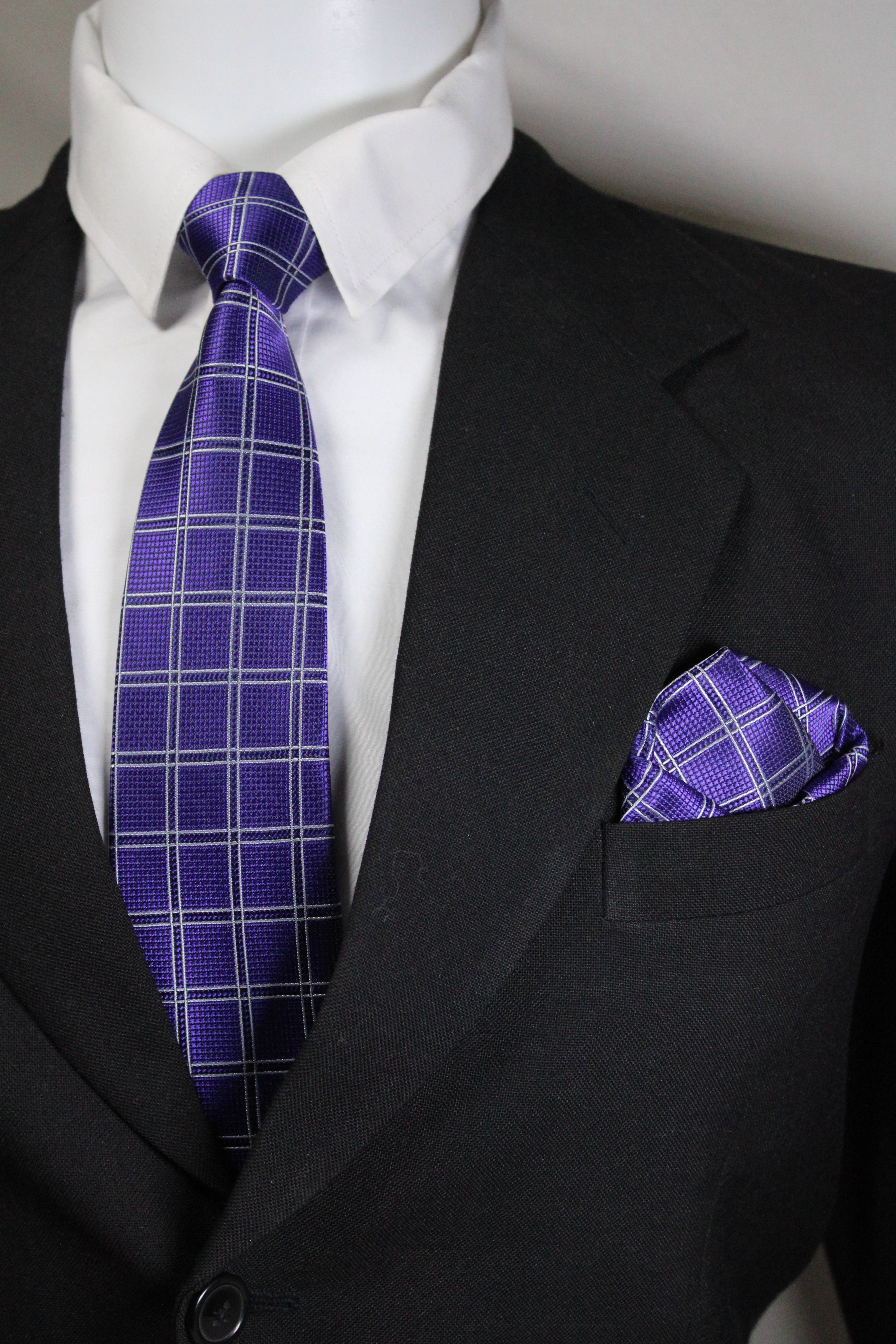 Close-up of a purple plaid tie and pocket square on a black suit jacket Tie Benon