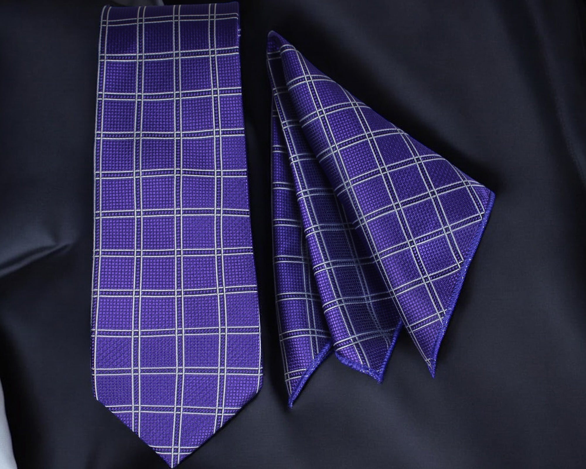 Purple checkered tie and pocket square on a black fabric background Tie Benon