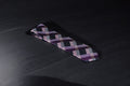 A purple and navy checkered tie laid out on a dark surface.