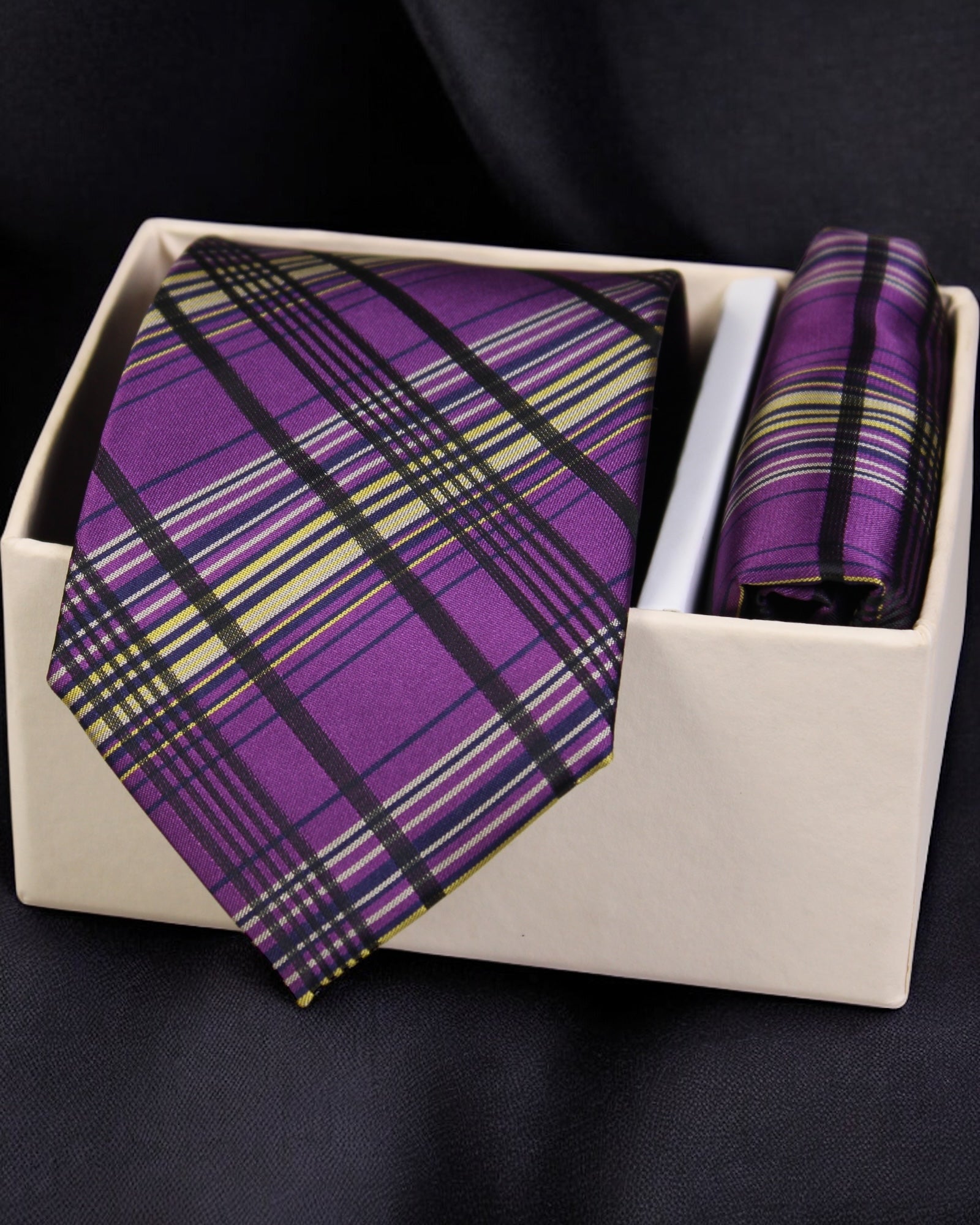 Purple plaid tie and pocket square set in a white box on a dark background