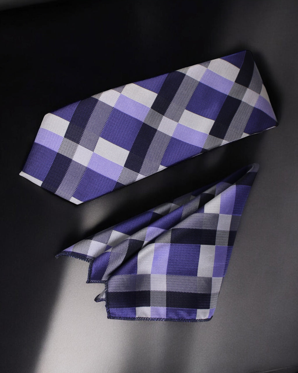 Plaid tie with purple, gray, and black pattern on a dark background