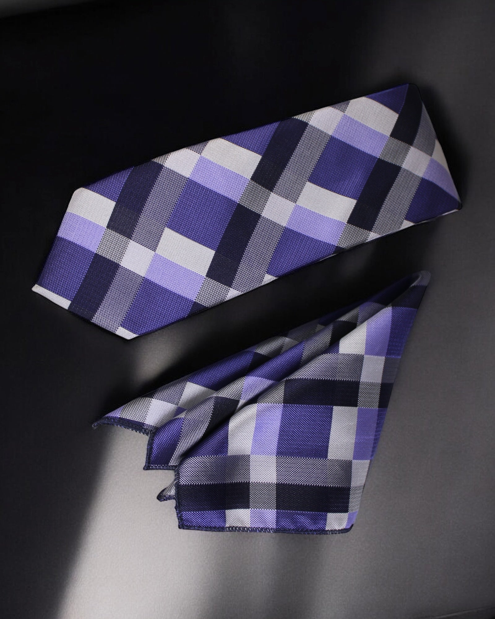 Plaid tie with purple, gray, and black pattern on a dark background