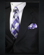 Black suit with a purple and gray checkered tie and matching pocket square.
