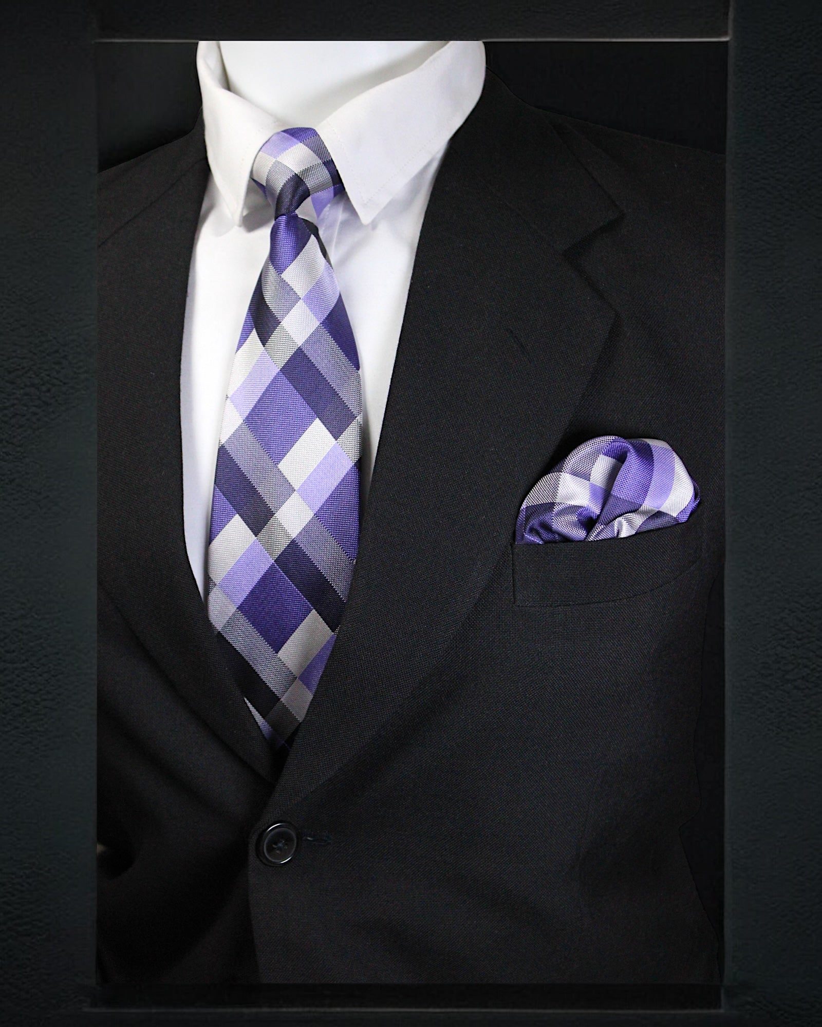 Black suit with a purple and gray checkered tie and matching pocket square.