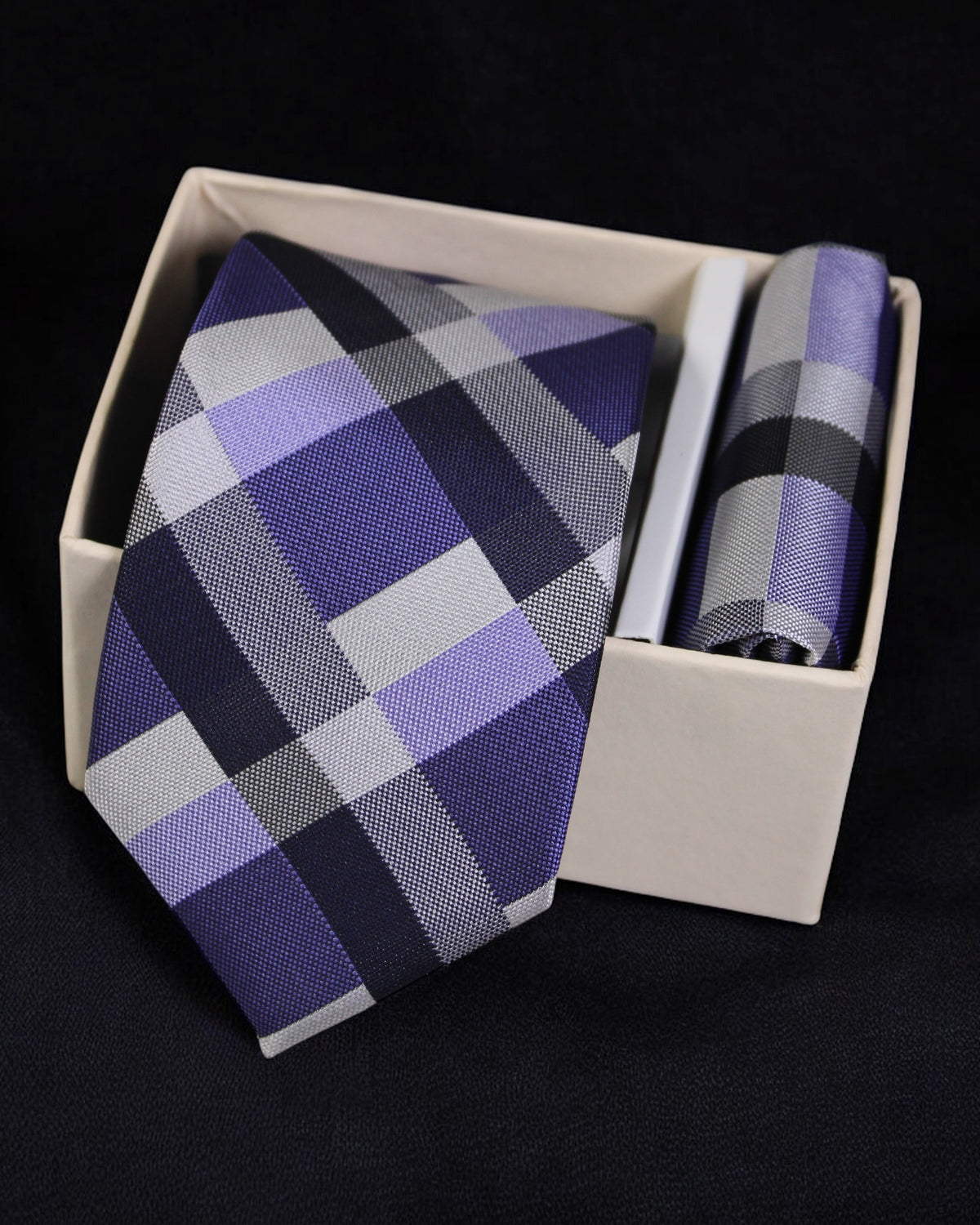 Plaid tie and pocket square set in a white box on a black background