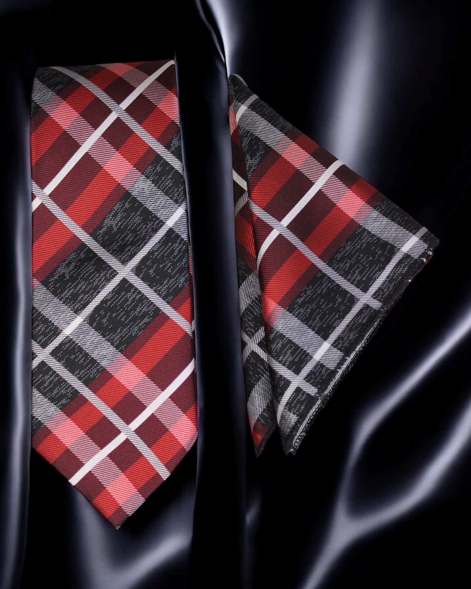 Red, black, and gray plaid tie and pocket square on a dark fabric background Tie Benon