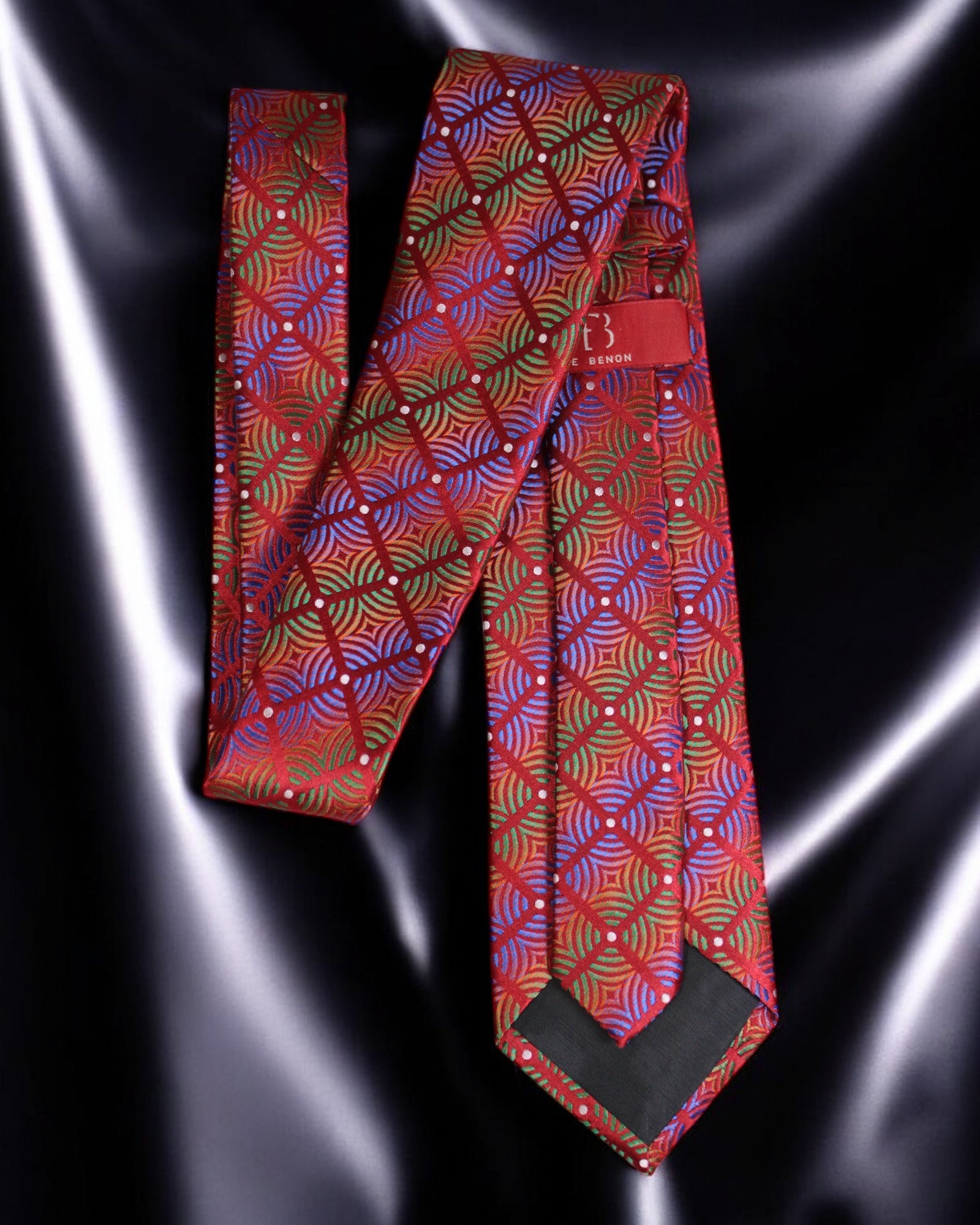 Red patterned tie on a reflective black surface Tie Benon