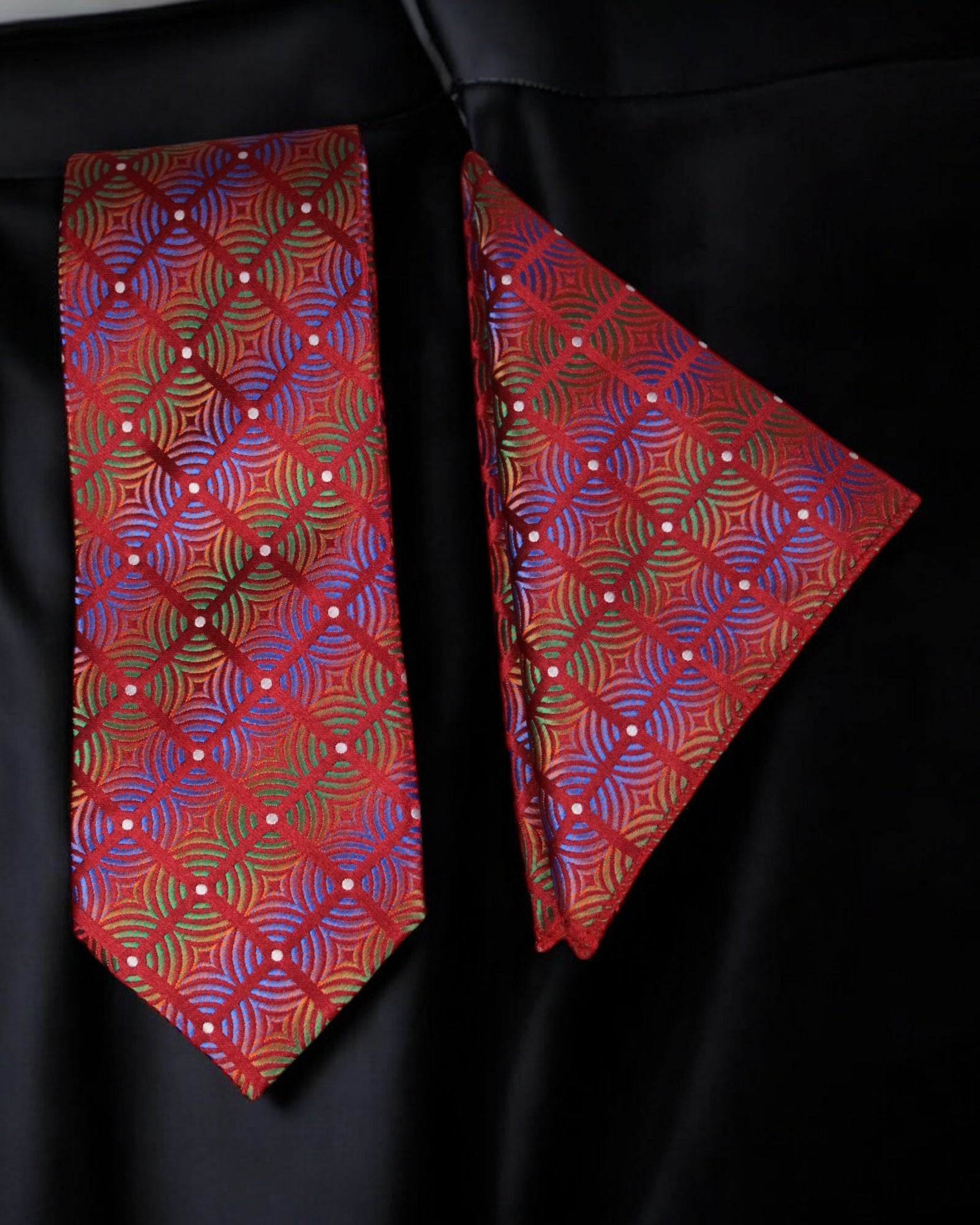 Red patterned tie and matching pocket square on a black background Tie Benon