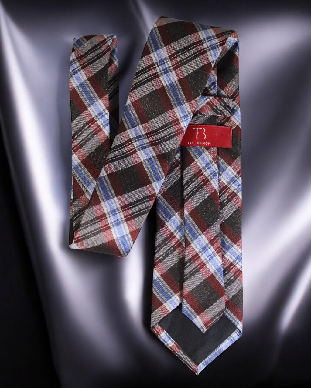 Plaid tie with a red tag on a metallic surface Tie Benon
