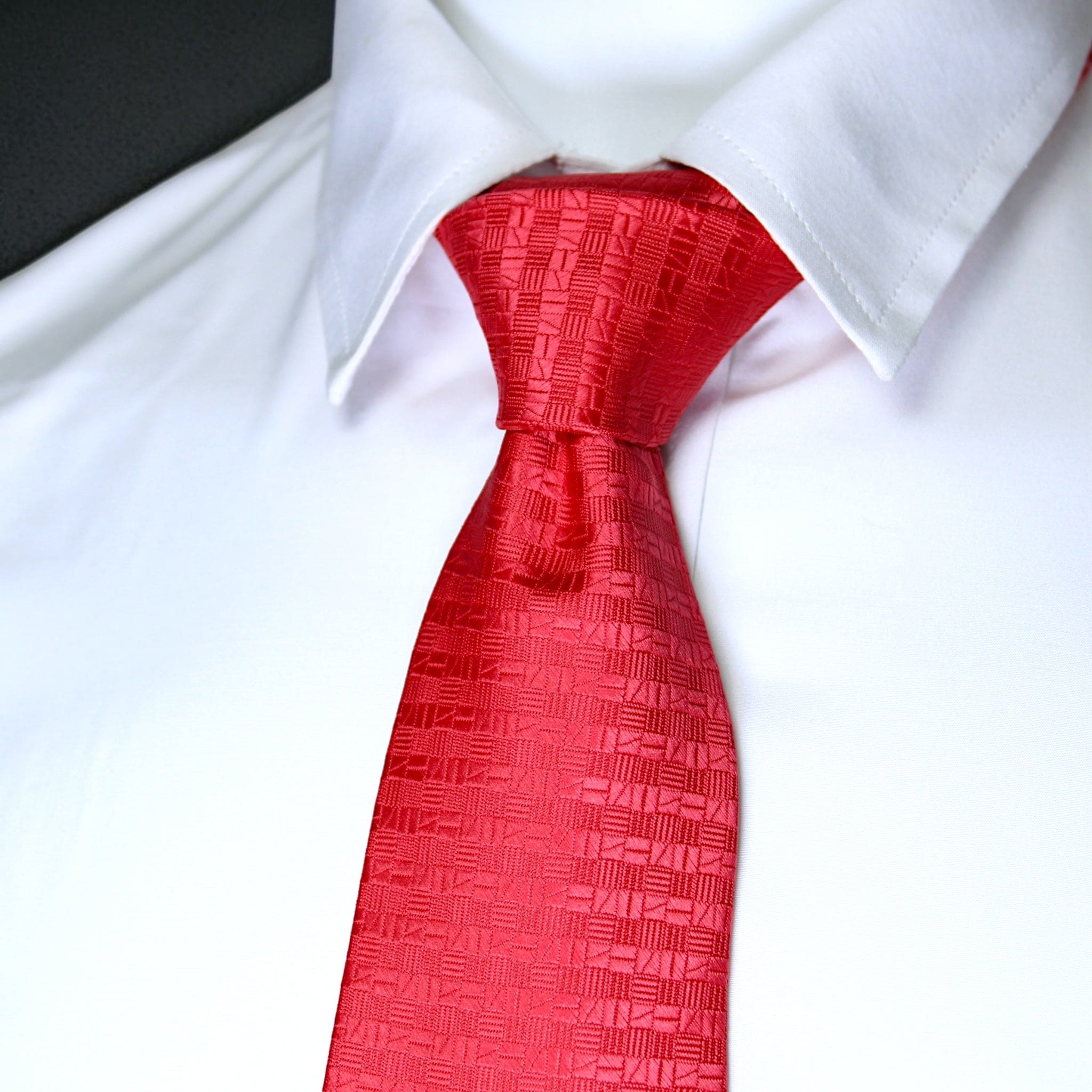 Red patterned tie on a white shirt against a black background