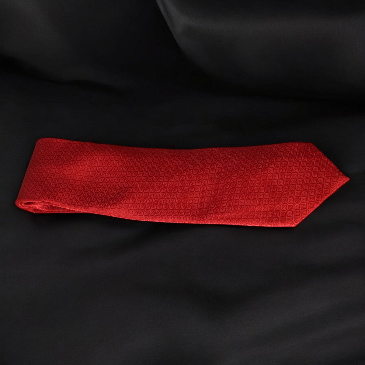 Red textured tie on a black fabric background